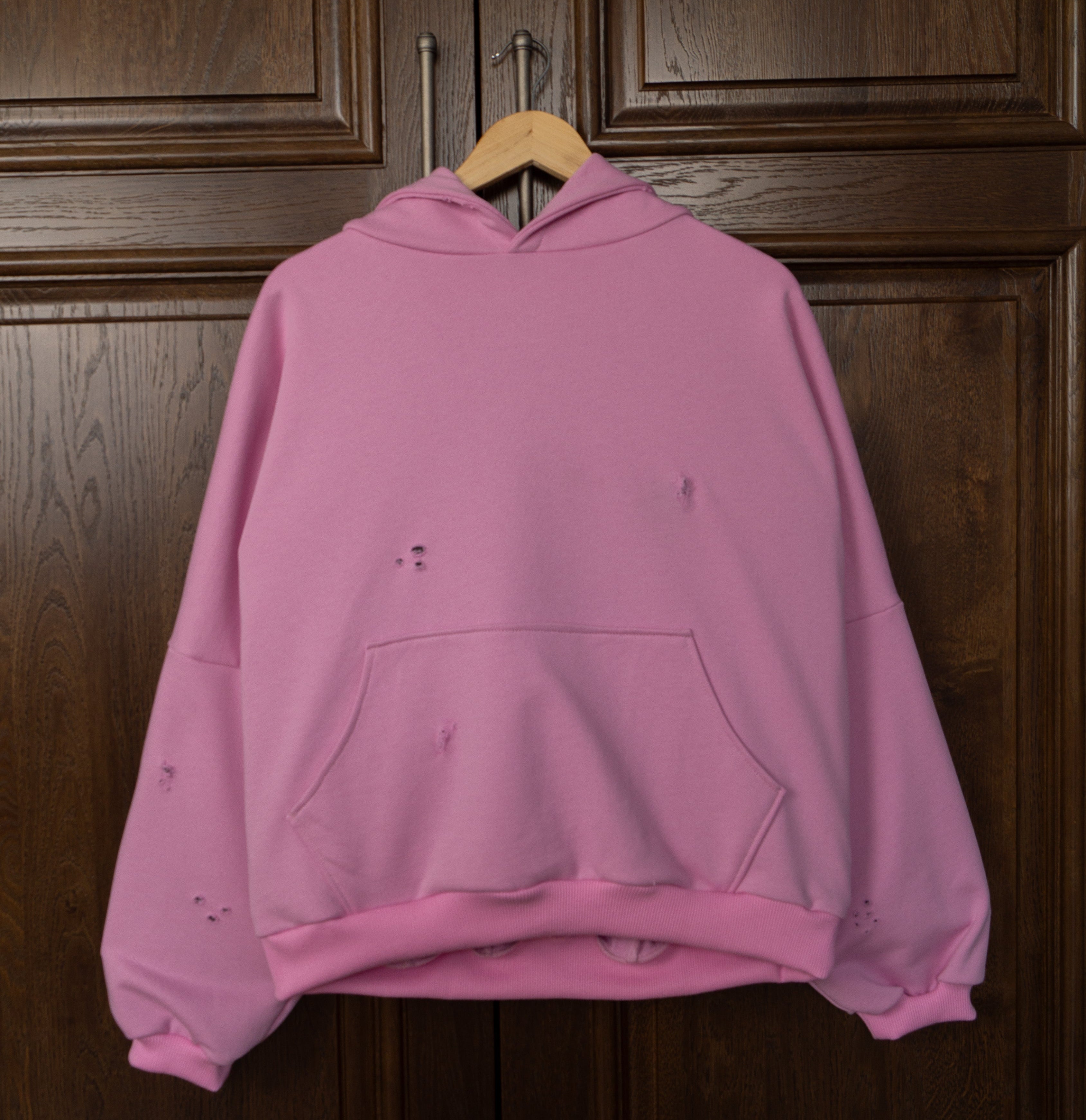 Pink hoodie hanging on a wooden door